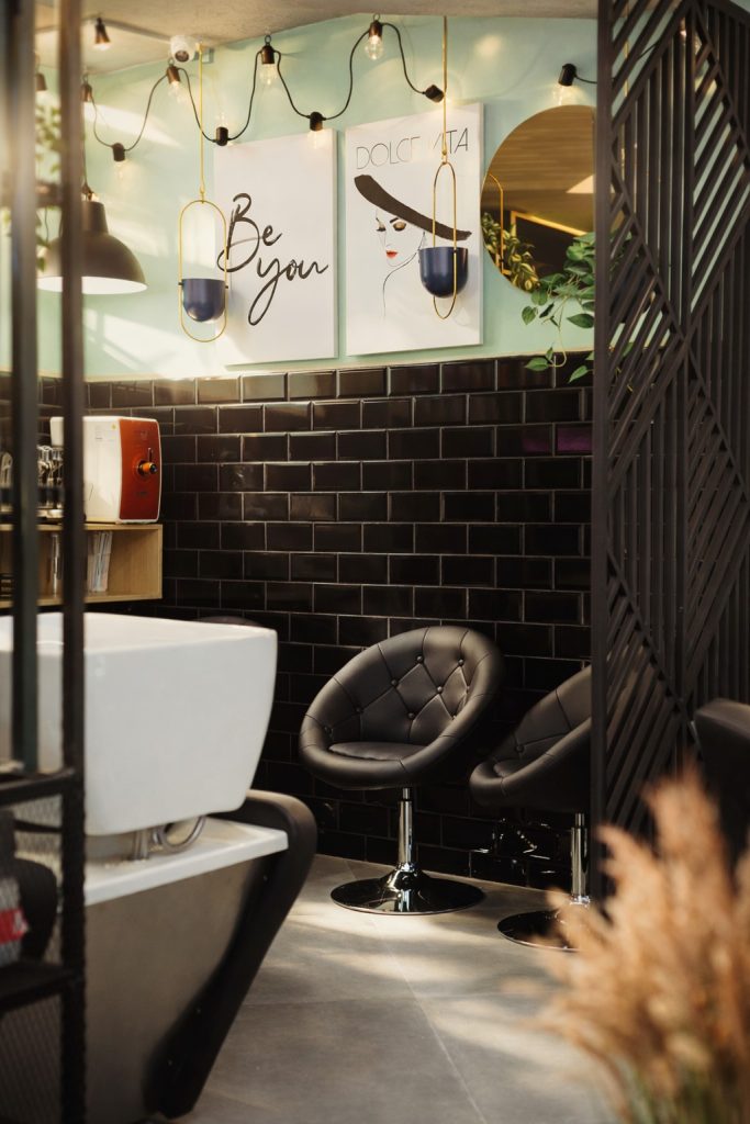 zona de spalare salon Lumi Hair Style cu scaune negre perete cu faianta neagra si accente decorative intr-un design modern si elegant